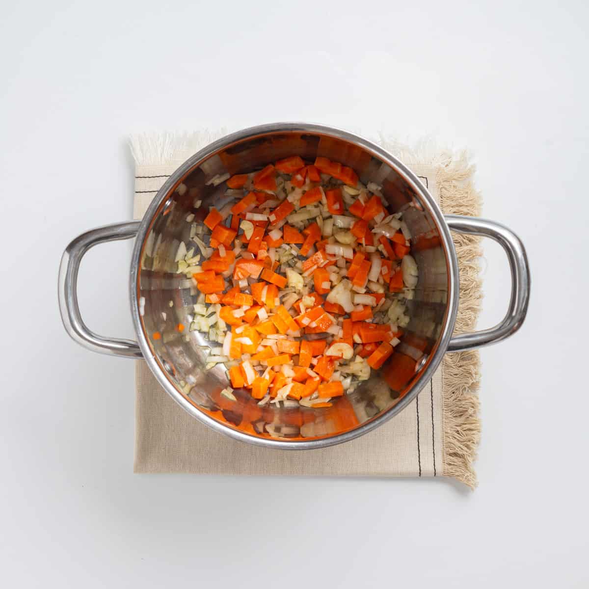 Overhead view showing carrots added to pot. 