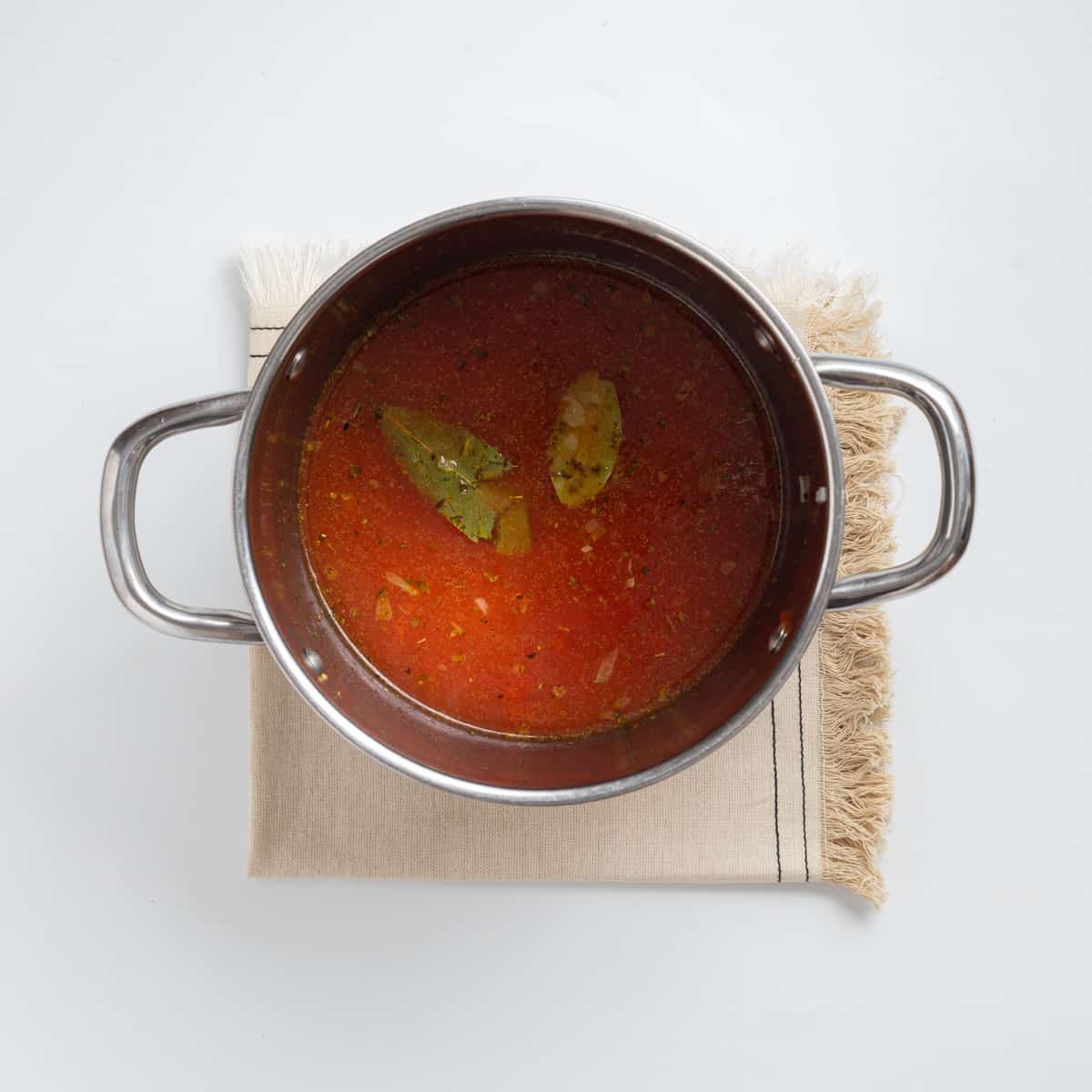 Overhead view showing tomatoes and broth added to pot. 