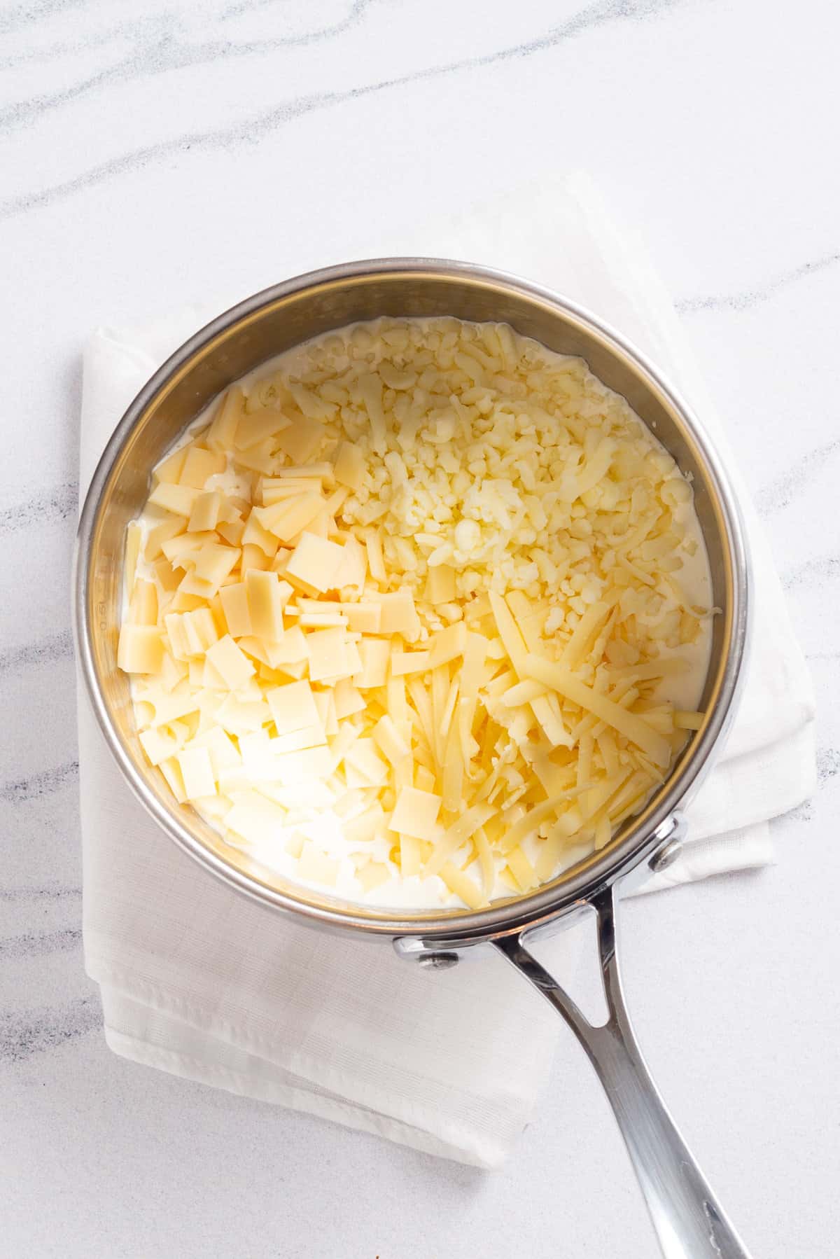 An image of 3 types of cheese combined in a saucepan.