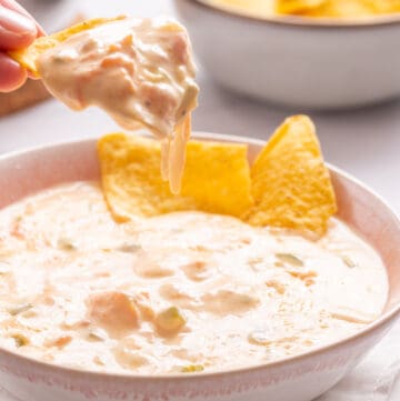 A close up image of spicy cheese dip with tortilla chips.