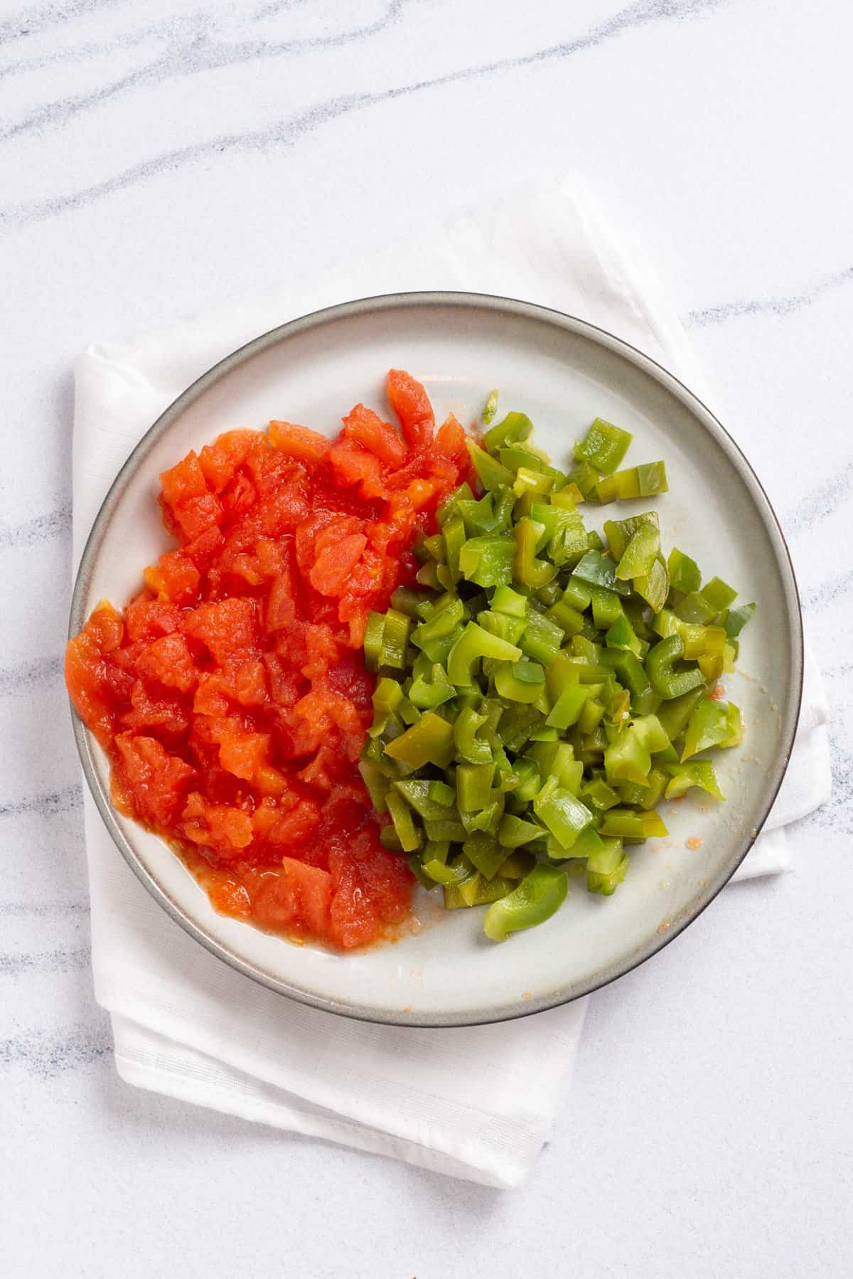 An image of peeled and dices roasted green pepper and tomatoes.
