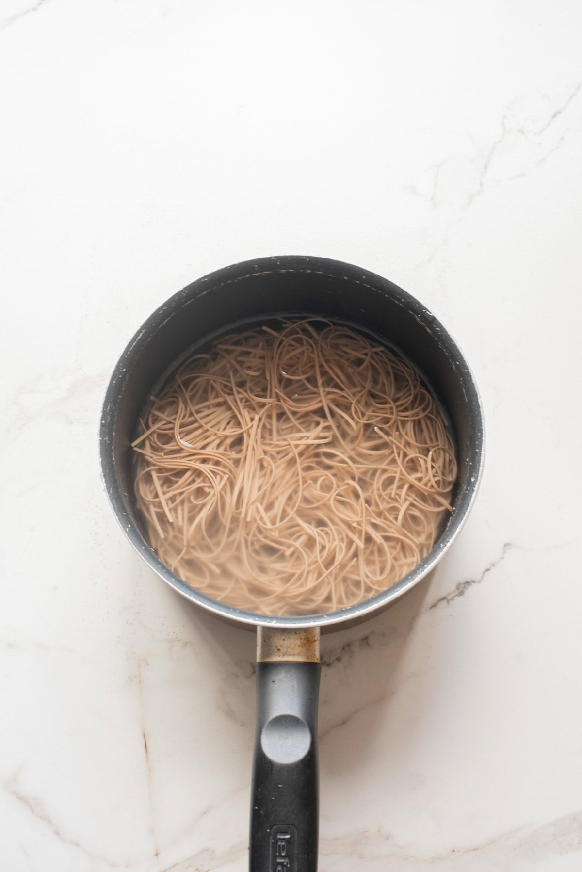 An overhead image of cooking the noodles in a saucepan.