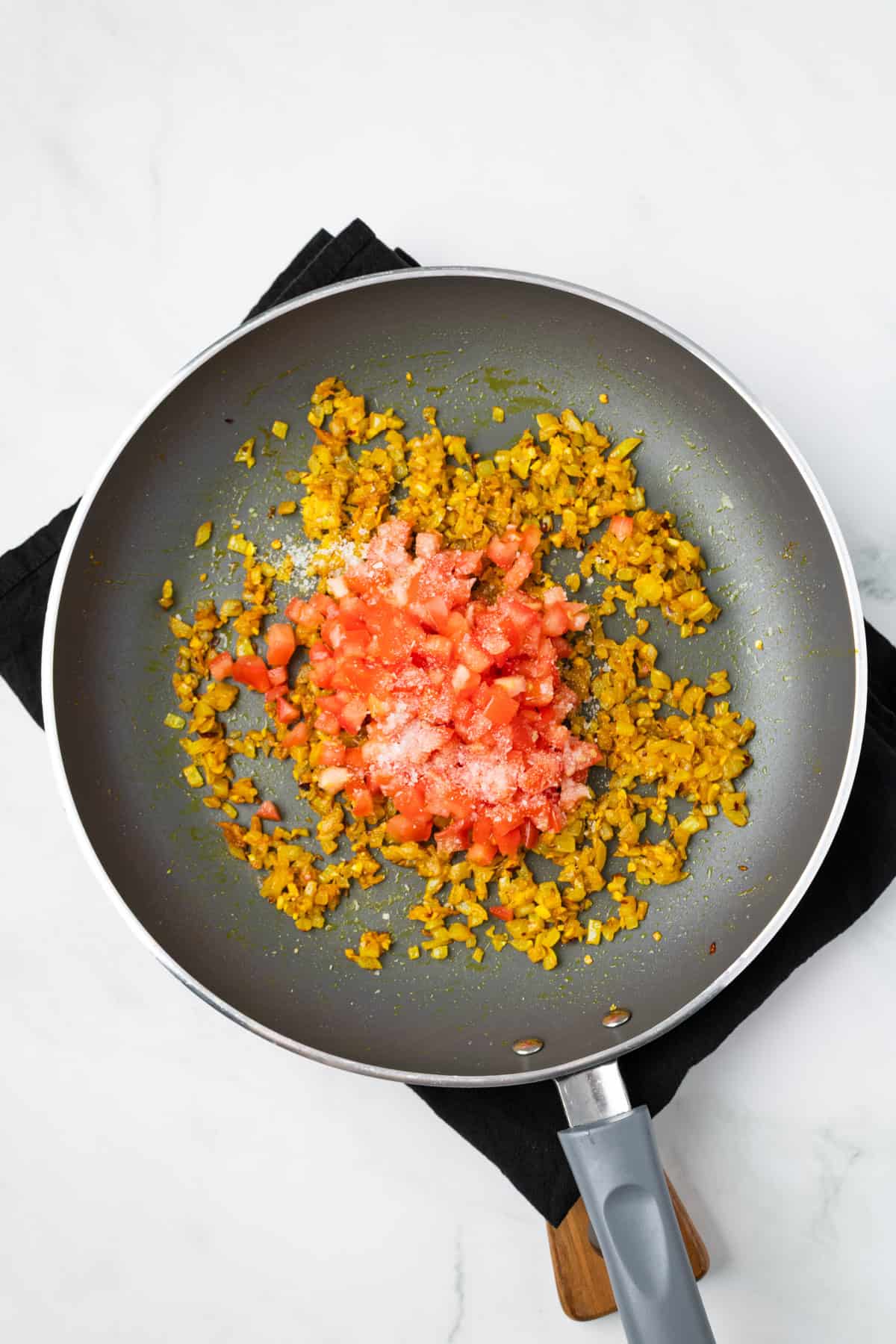 An overhead image of adding tomatoes to the mixture.