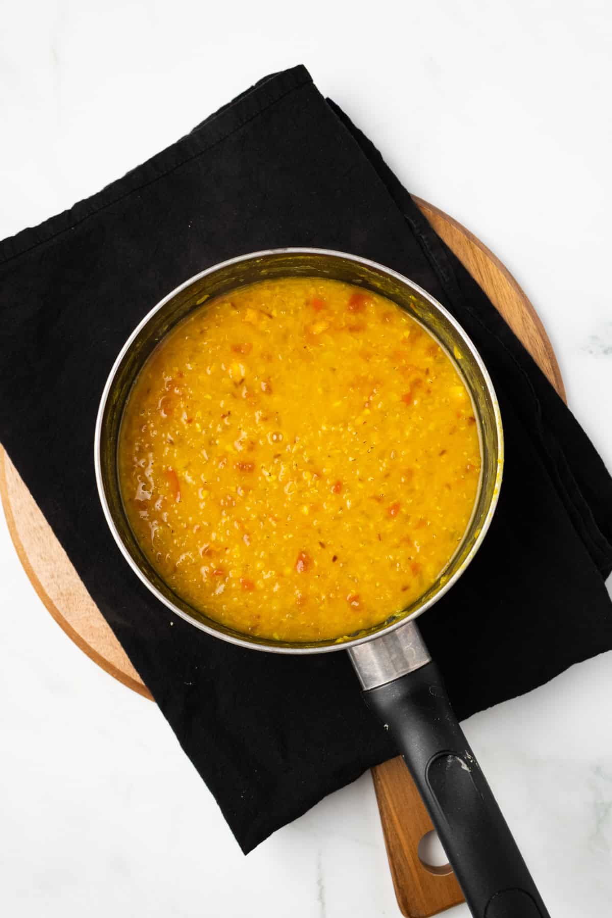 An overhead image of adding red lentils to the mixture.