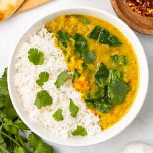 An overhead image of spinach dal over white rice in a bowl.