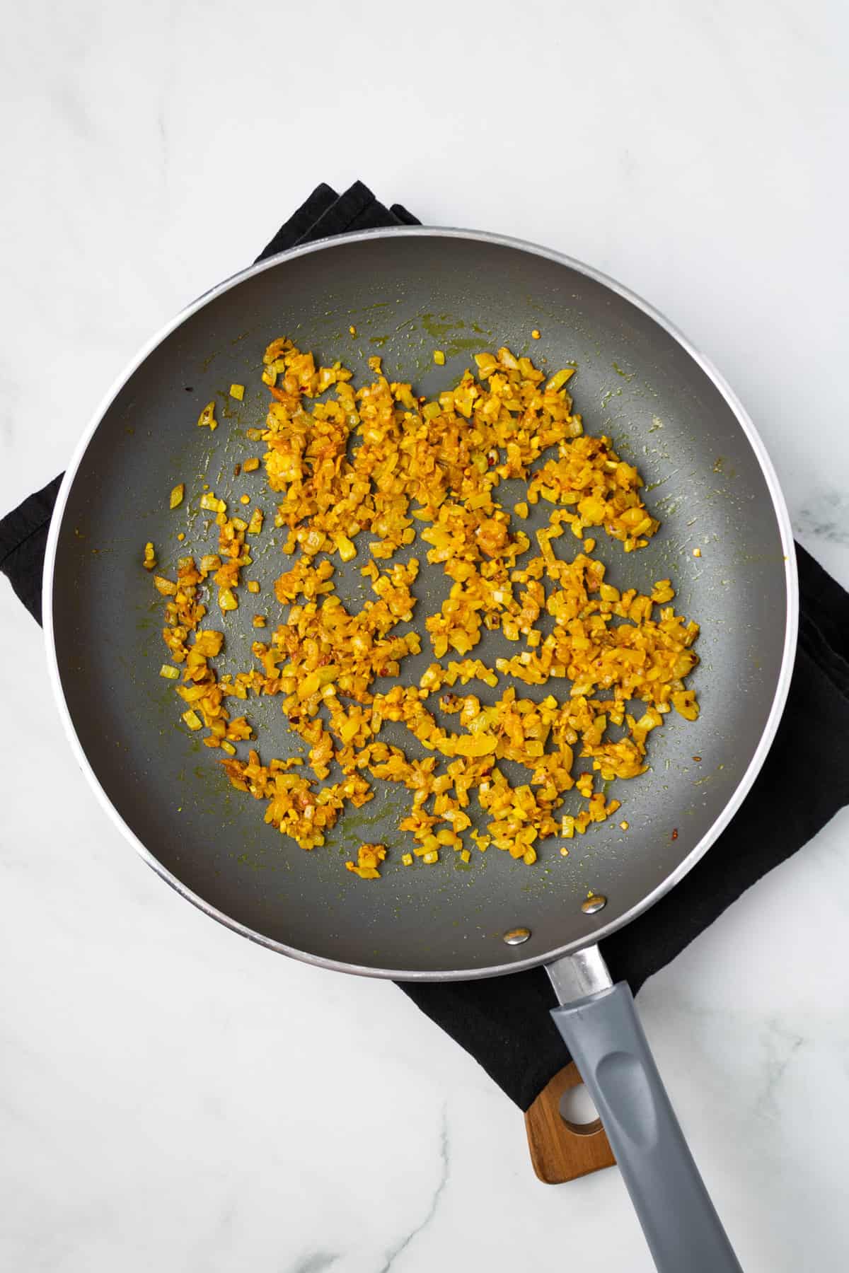 An overhead image simmering the spices with onions and garlic.