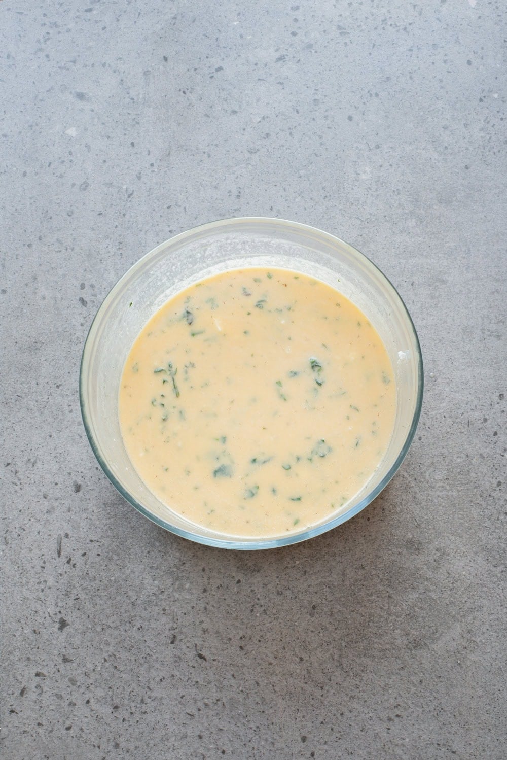 An overhead image of adding the feta cheese, spinach, and seasonings to the mixture.