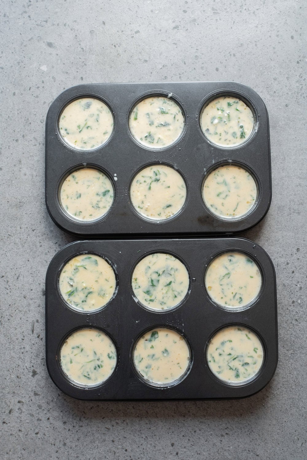 An overhead image of filling two muffin tins with the mixture.