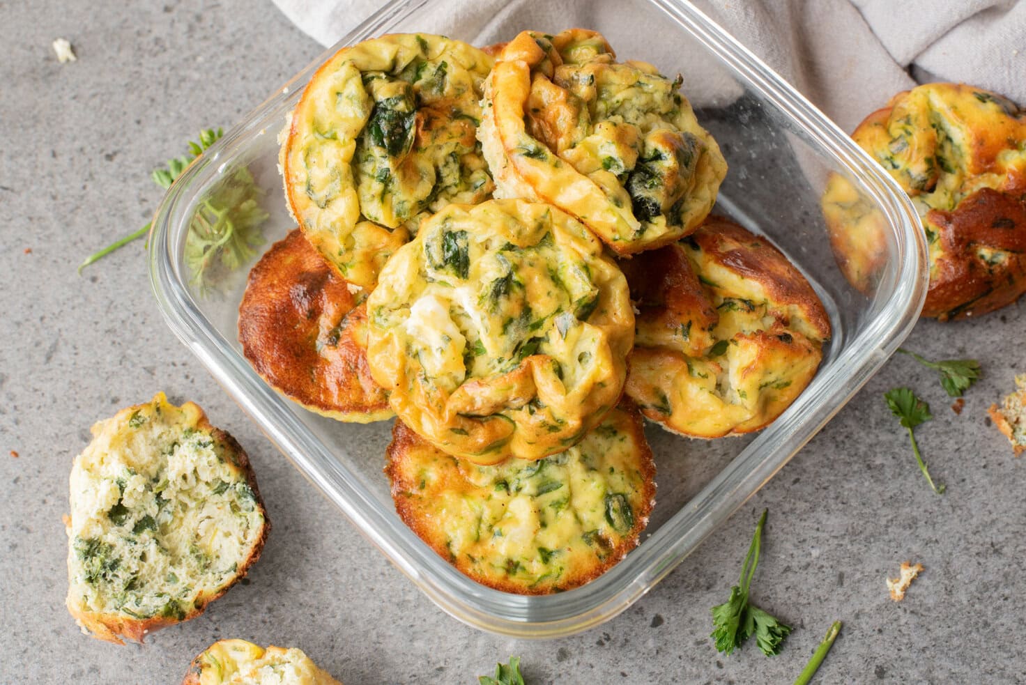 An overhead image of spinach and cottage cheese muffins in a container.