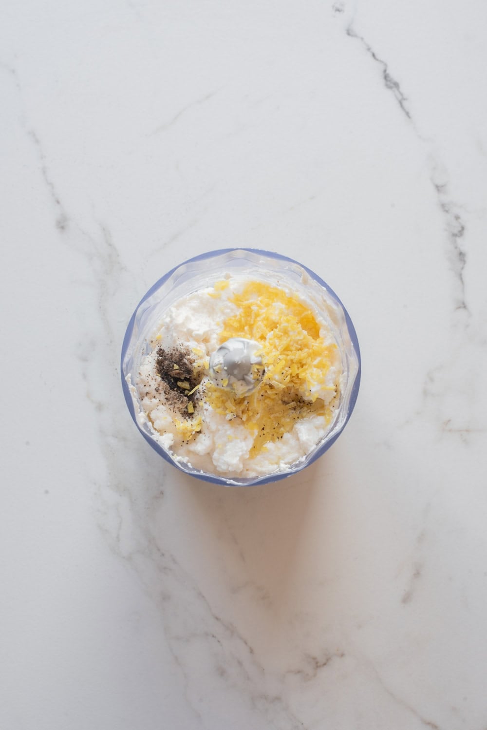 Ricotta, lemon zest, olive oil, and seasonings in a food processor before blending.