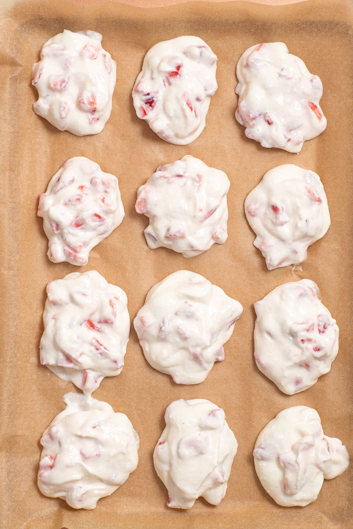 Strawberry cottage cheese mixture scooped into mounds on parchment paper before freezing.