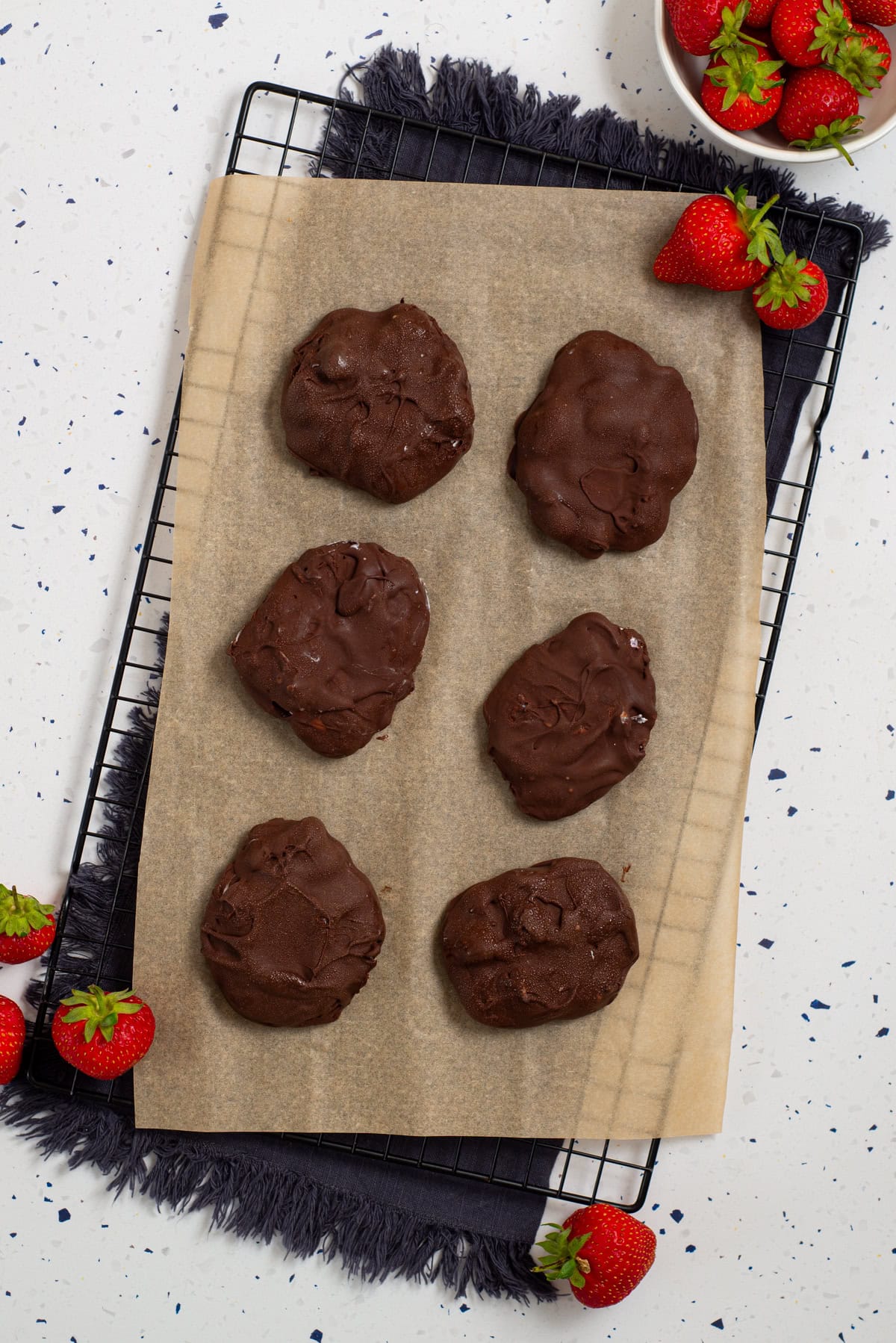 Chocolate-covered strawberry cottage cheese clusters setting on parchment paper.
