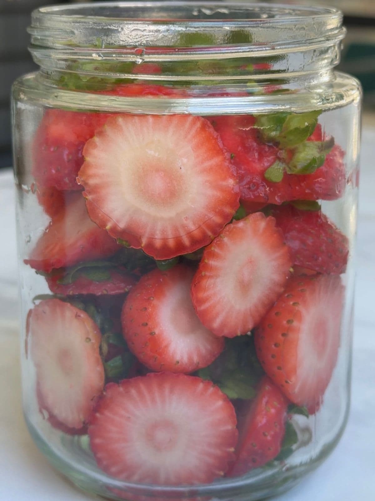 Strawberry tops added to the jar.
