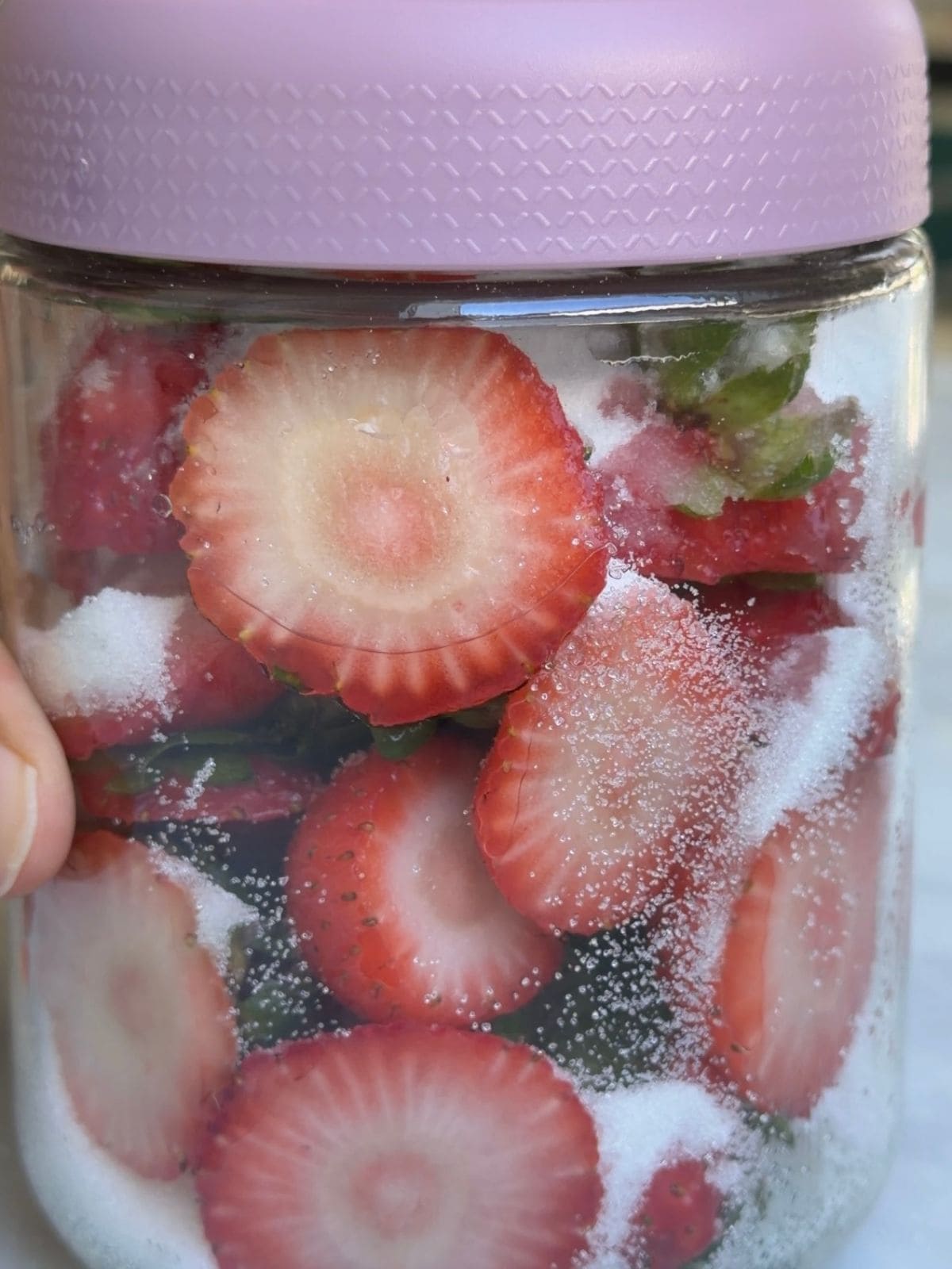 Strawberry tops loaded with sugar in the jar.