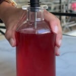 Hand holding a syrup container with strawberry syrup