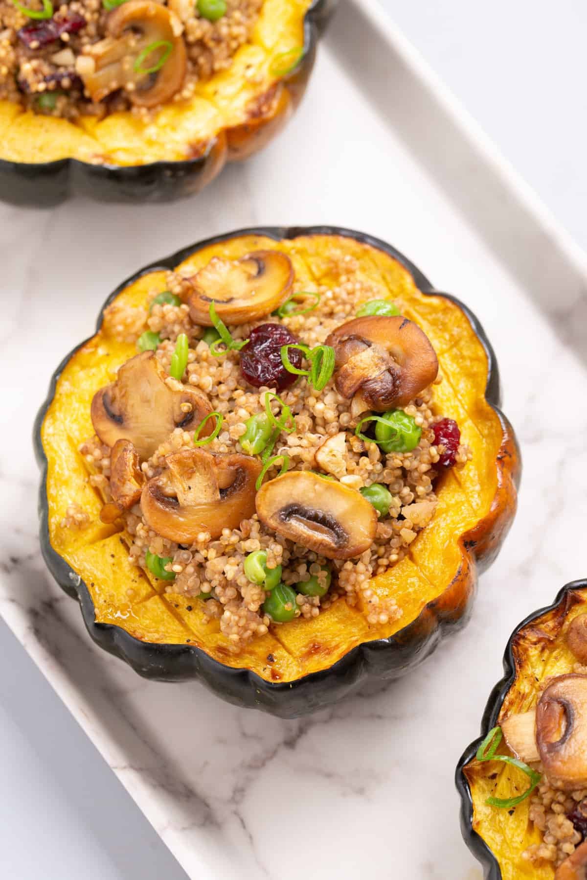 Close up view of stuffed acorn squash on a white platter.