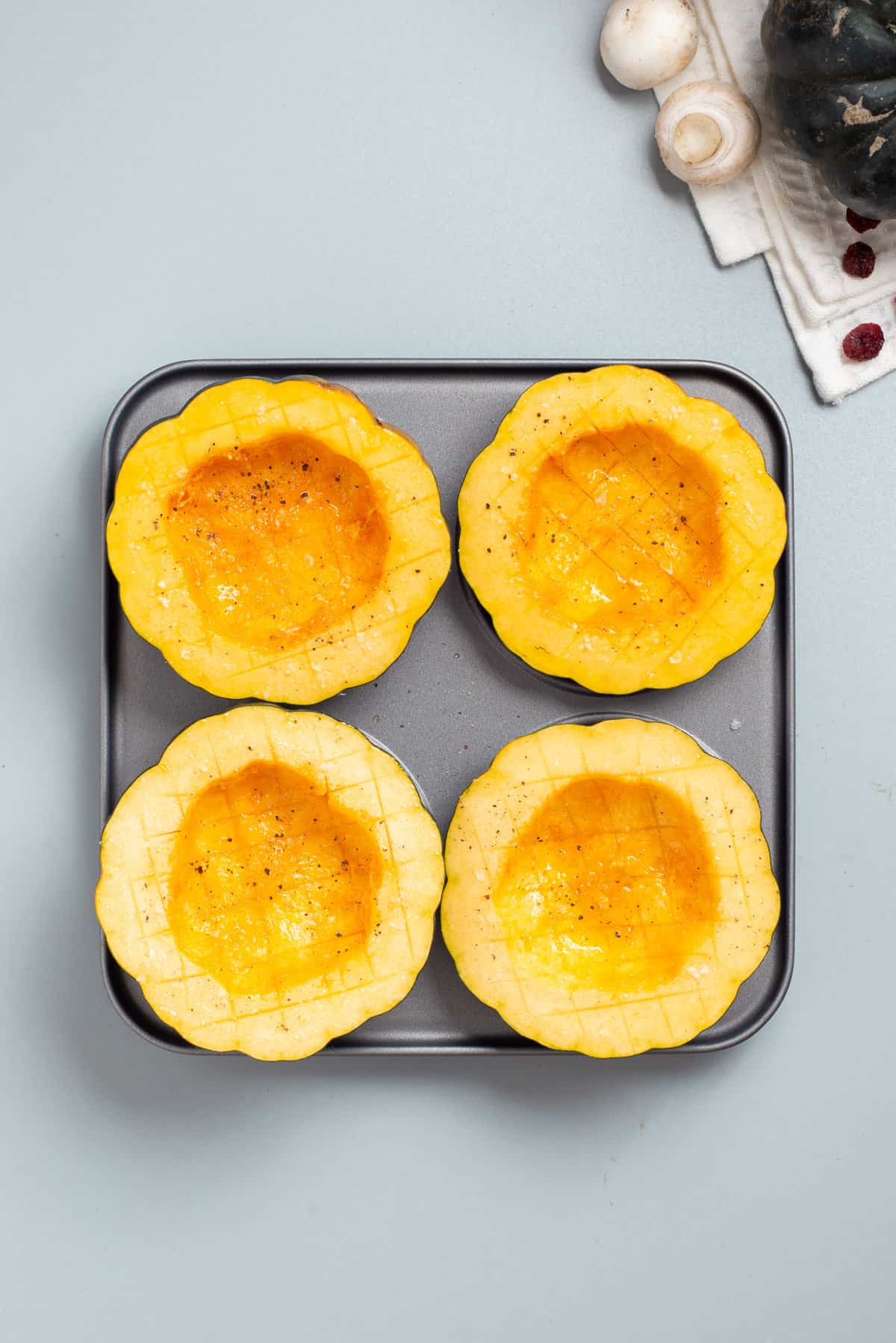 Overhead view of four halves of acorn squash on a baking sheet.