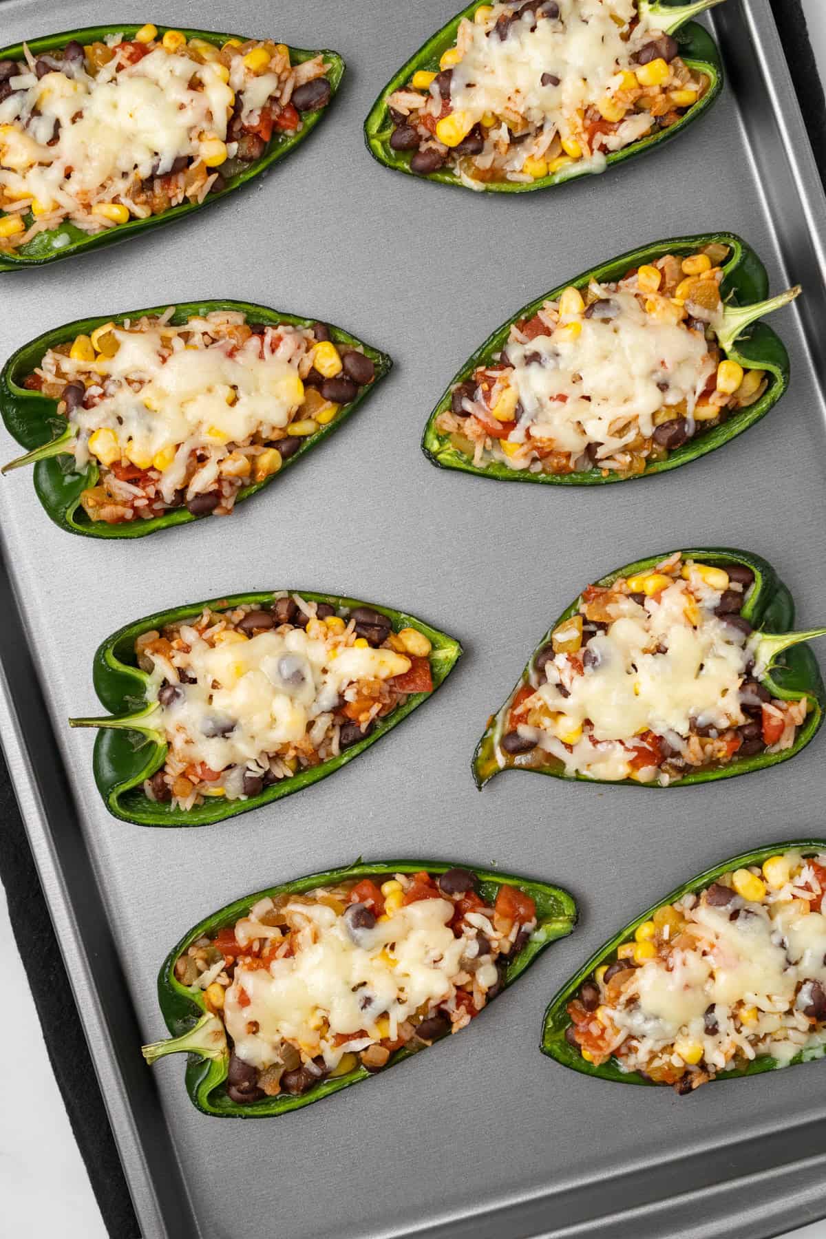 An overhead image of baked stuffed poblano peppers on a baking sheet.
