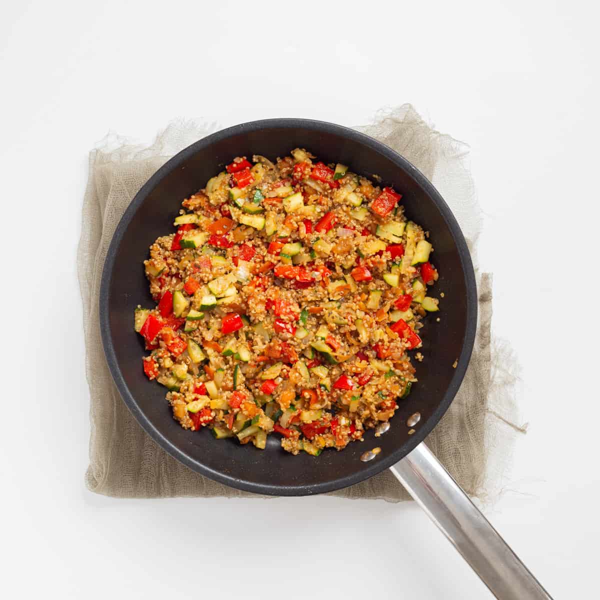 An image of sauteed vegetables mixed with quinoa and italian seasoning on a skillet.