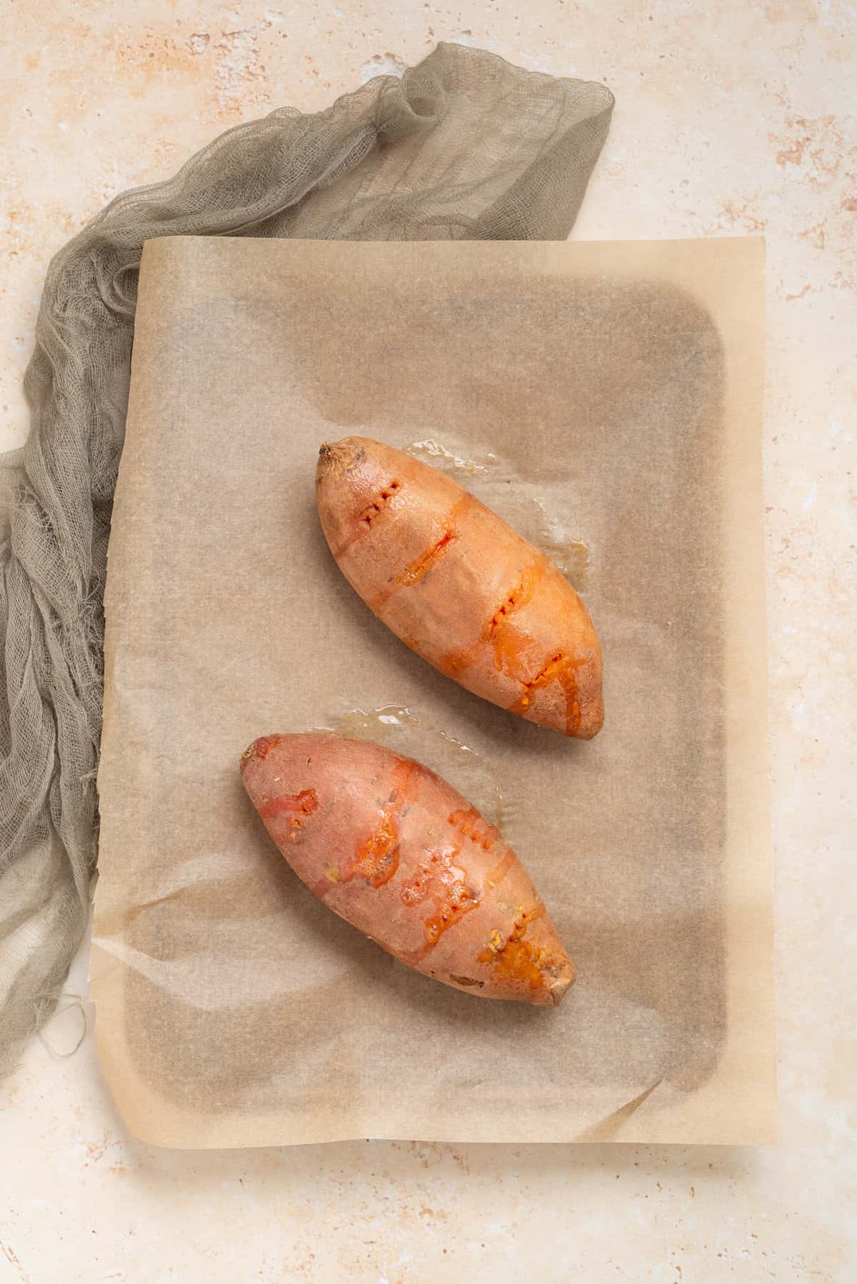 An image of pierced sweet potatoes in a large baking sheet.