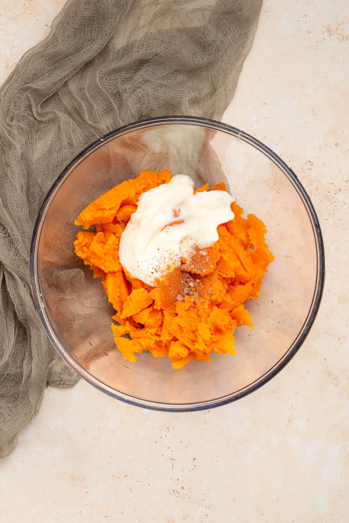 An image of sweet potato flesh, sour cream, salt, and pepper in a mixing bowl.