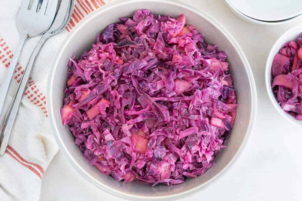 Overhead view of sweet and sour red cabbage with apples in a white bowl.