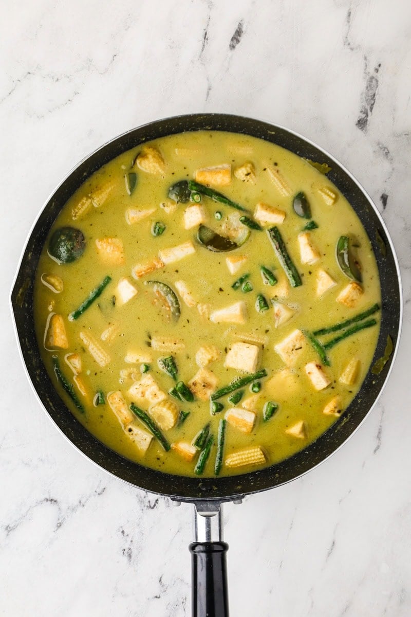 Tofu, longbeans, coconut sugar, and fish sauce to finish Thai green curry in a pan.