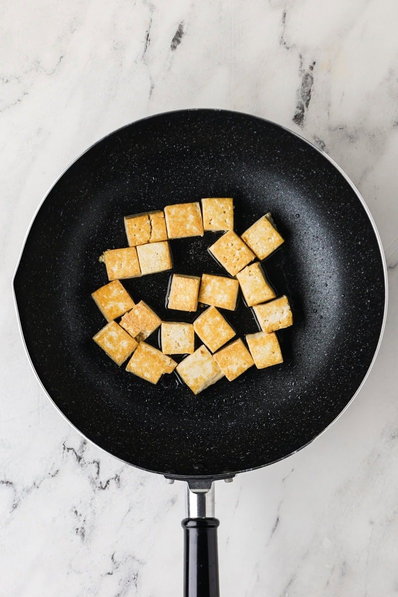 An overhead image of frying tofu on a skillet.