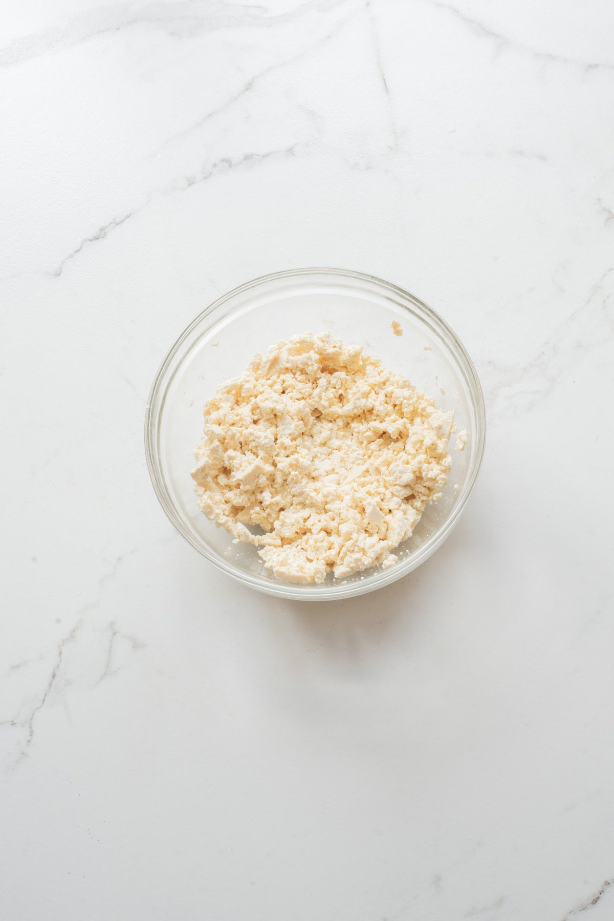 An overhead image of crushed tofu in a bowl.