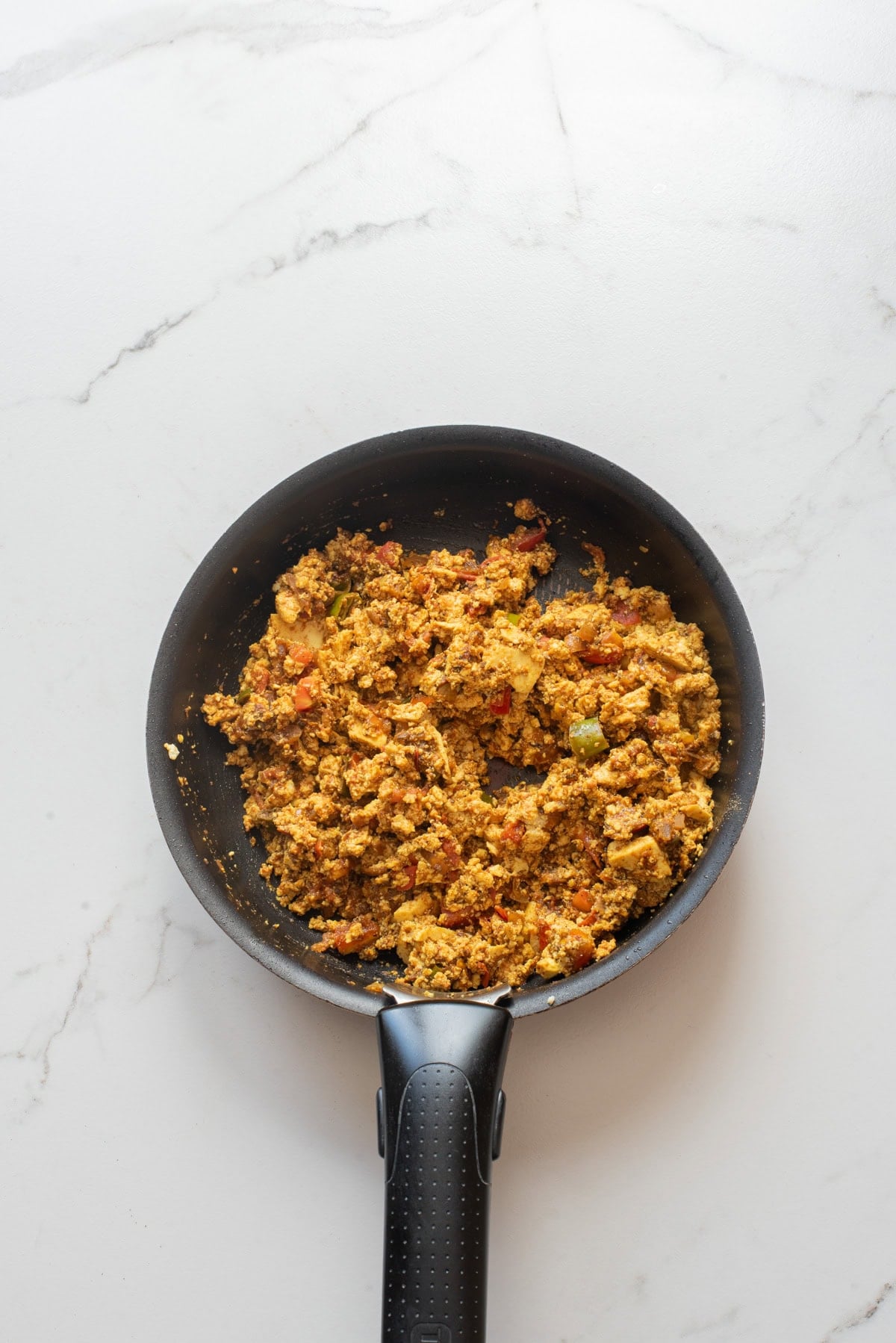 An overhead image of adding crumbled tofu on the pan.