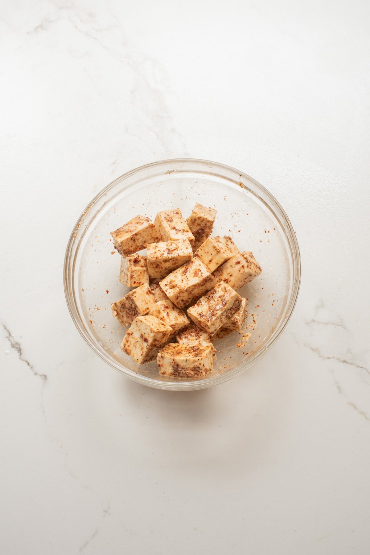 An overhead image of tossing seasoning on the tofu.