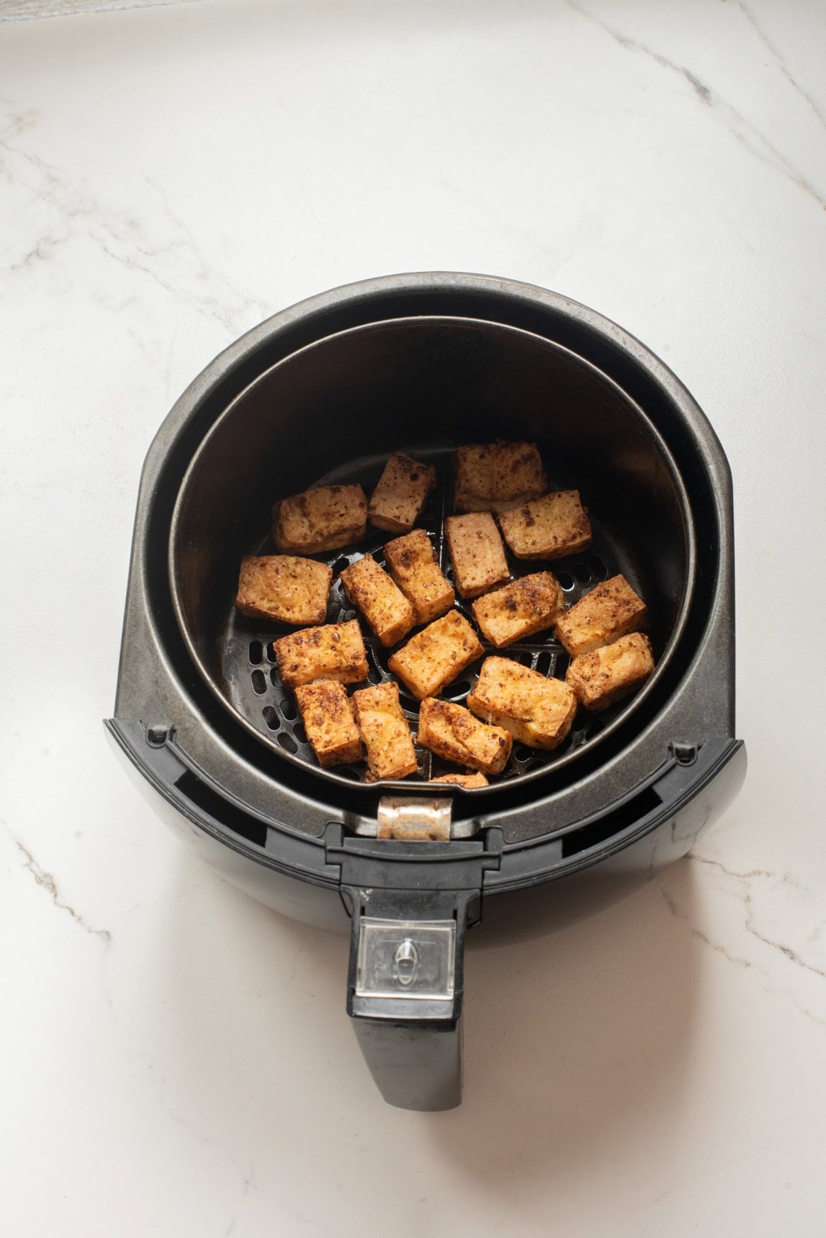 An overhead image of crisping up the tofu in the air fryer.