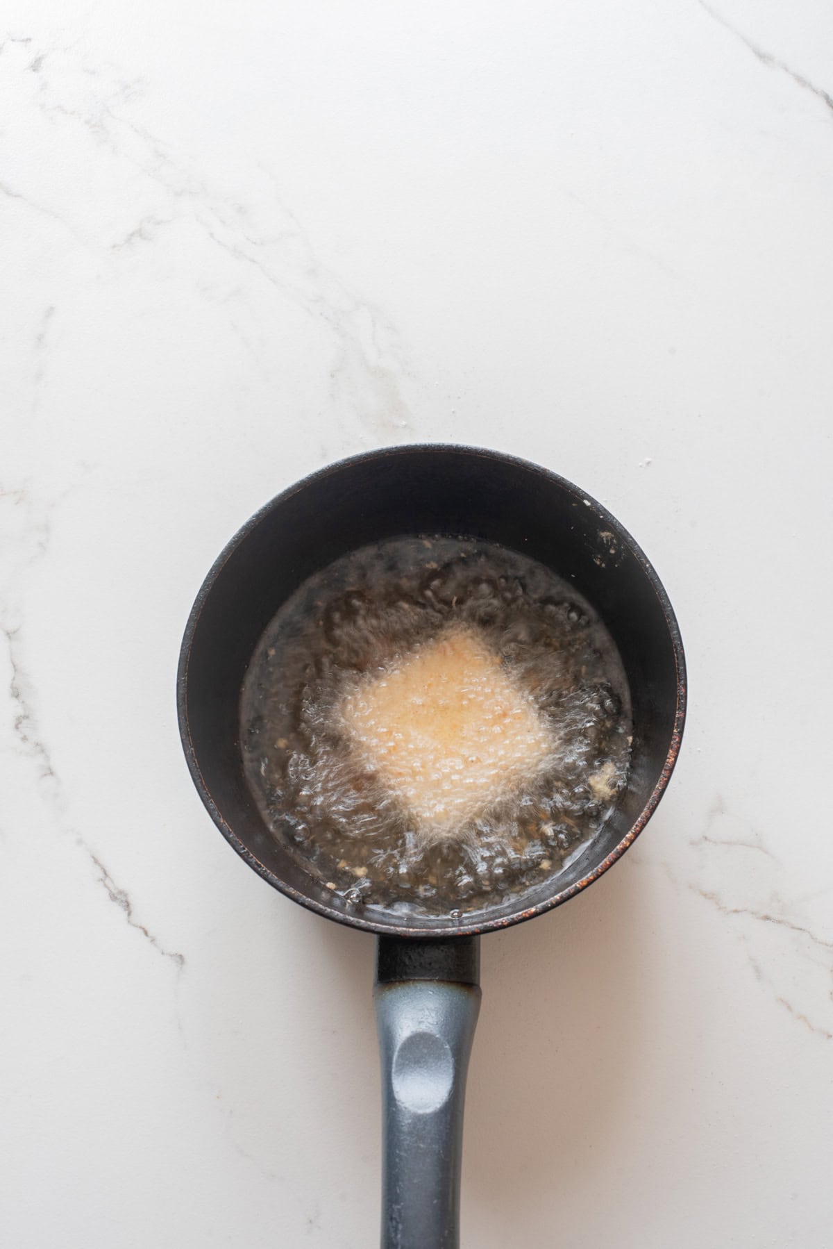 An overhead image of deep frying the breaded tofu.