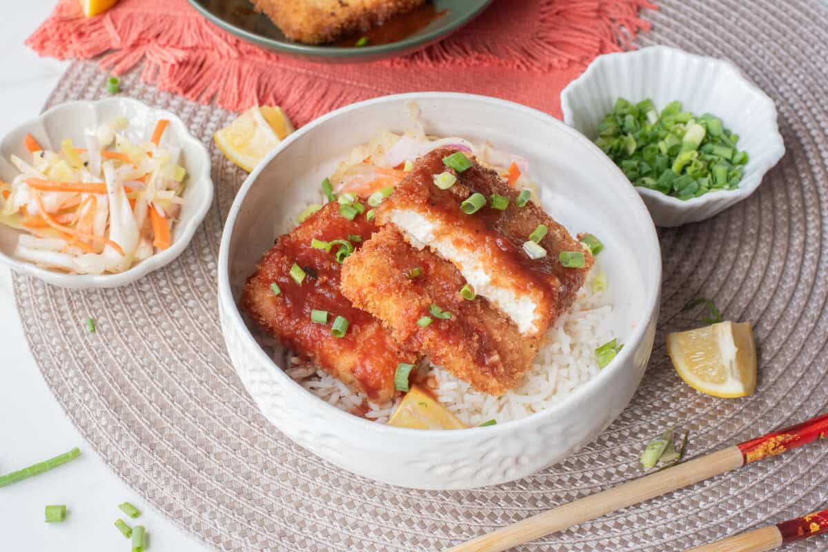 A close up image of tofu katsu served in a bowl over rice.