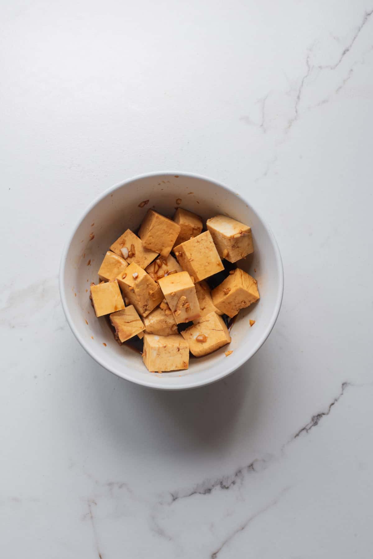 An overhead image of marinating tofu in a bowl.