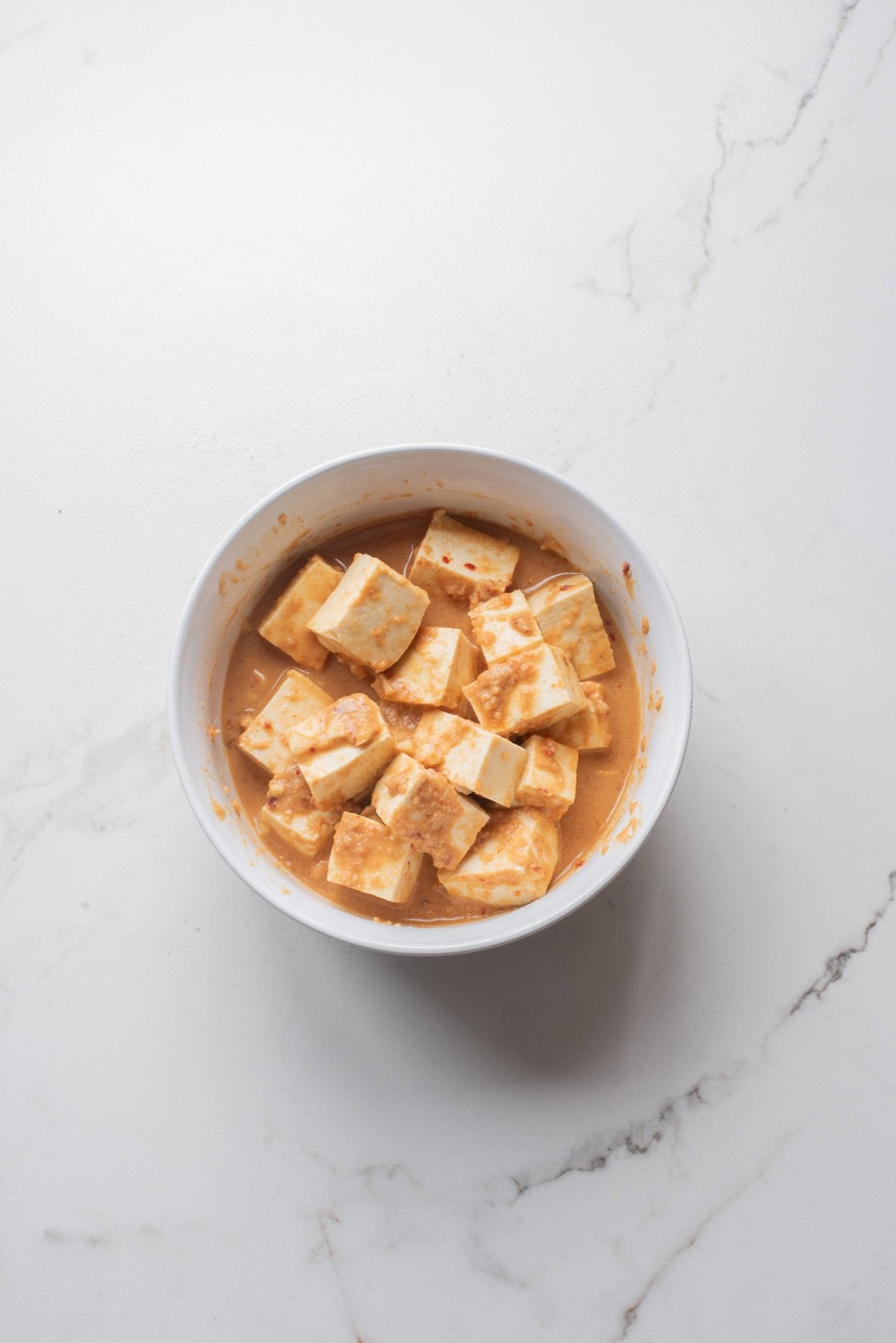 An overhead image of tofu marinating in a thai peanut mixture.