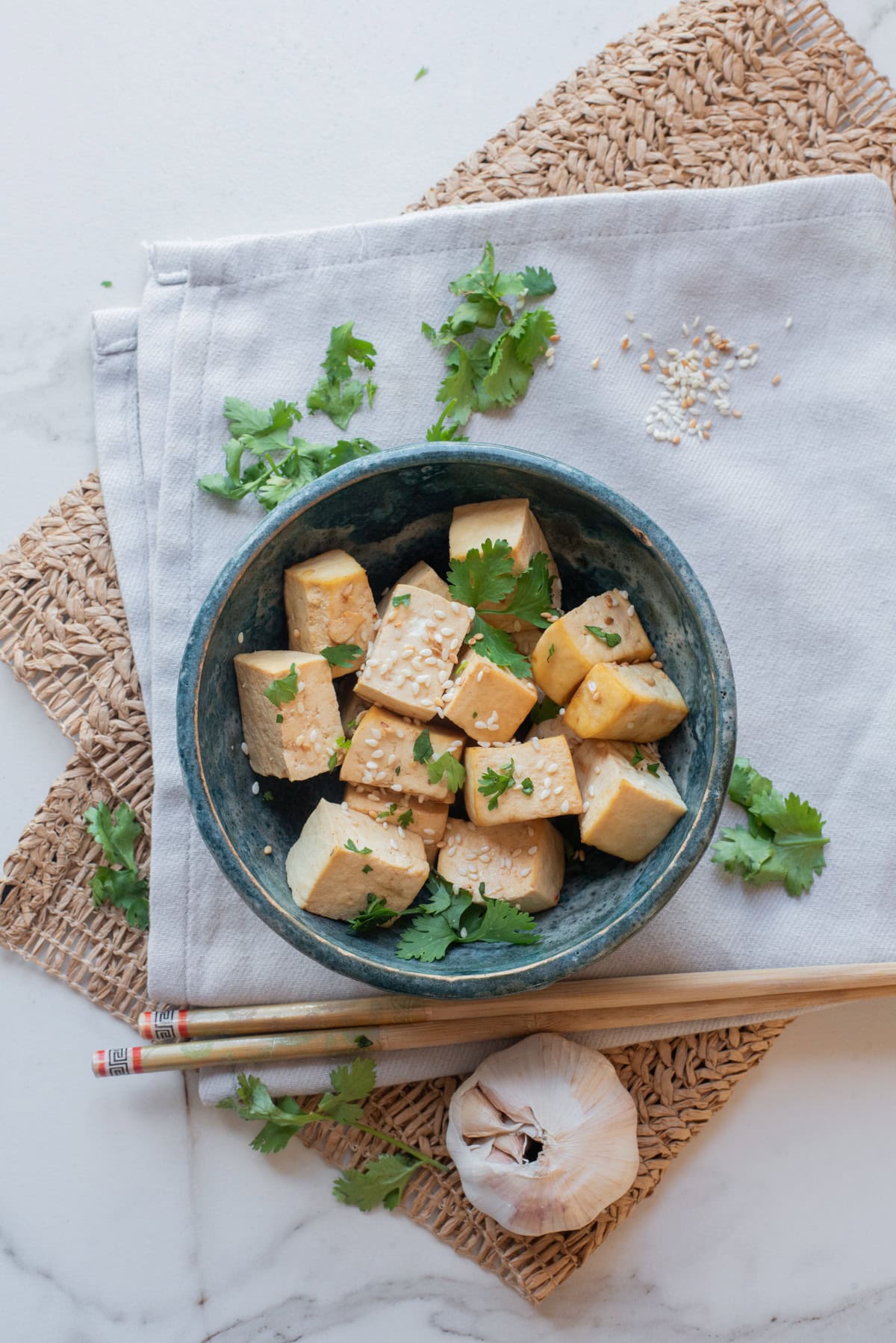 An overhead image of honey garlic tofu served on a plate with a garnish of fresh herbs.