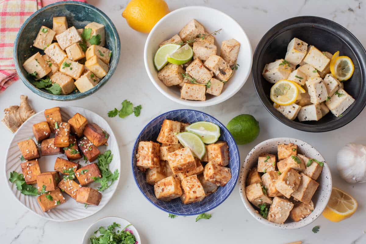 An overhead image of six tofu dishes served in different bowls.