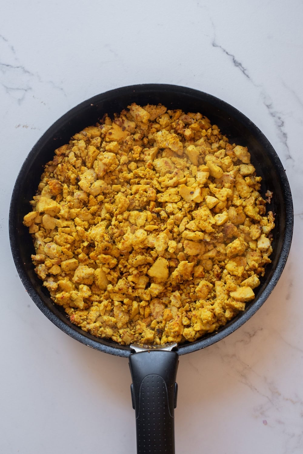 Seasoned tofu scramble cooking until golden and fluffy.