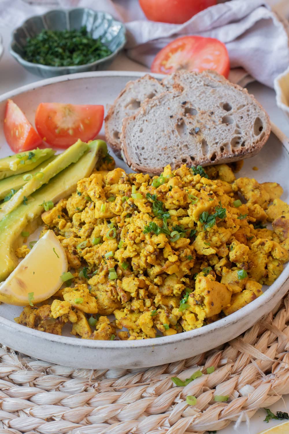 Golden tofu scramble garnished with herbs and served with toast and avocado.