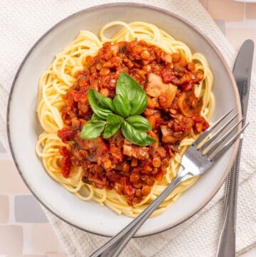 An overhead image of vegan bolognese with spaghetti in a serving bowl with a fork on the side.