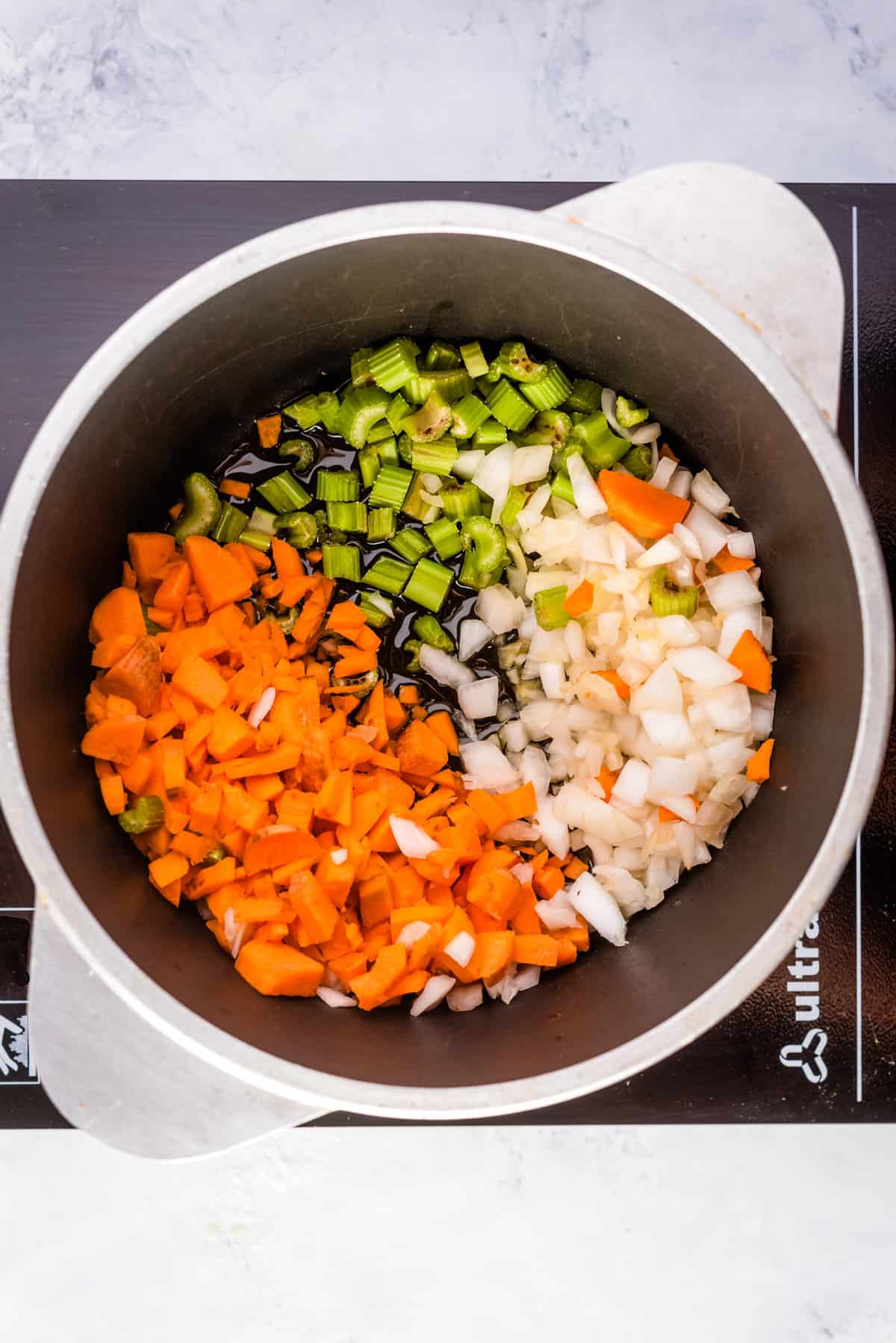 Overhead shot of mirepoix and garlic cooking in Dutch oven,