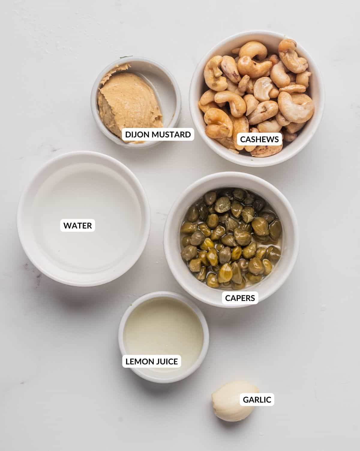 Overhead view of labeled ingredients for vegan Caesar dressing - check recipe card for details.