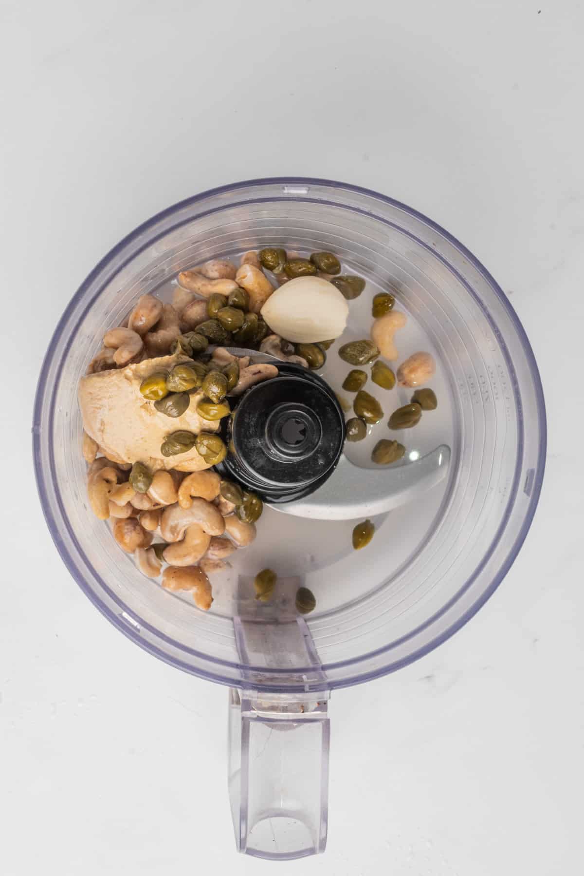 An image of vegan caesar salad dressing ingredients in a food processor before blending.