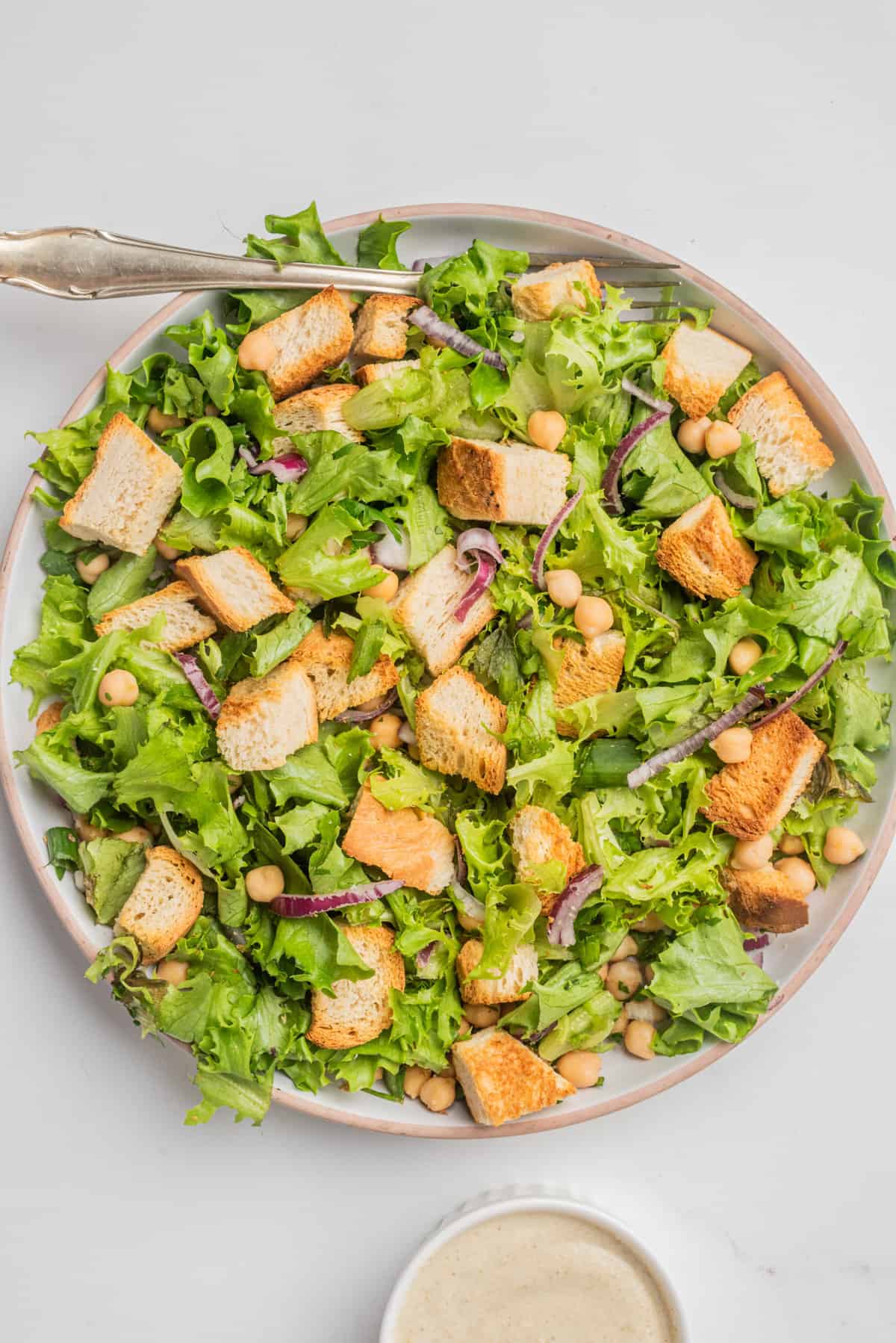 vegan caesar salad served in a in a bowl with the dressing on the side.