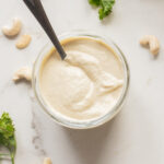 Creamy vegan Caesar dressing in a glass jar with a spoon.