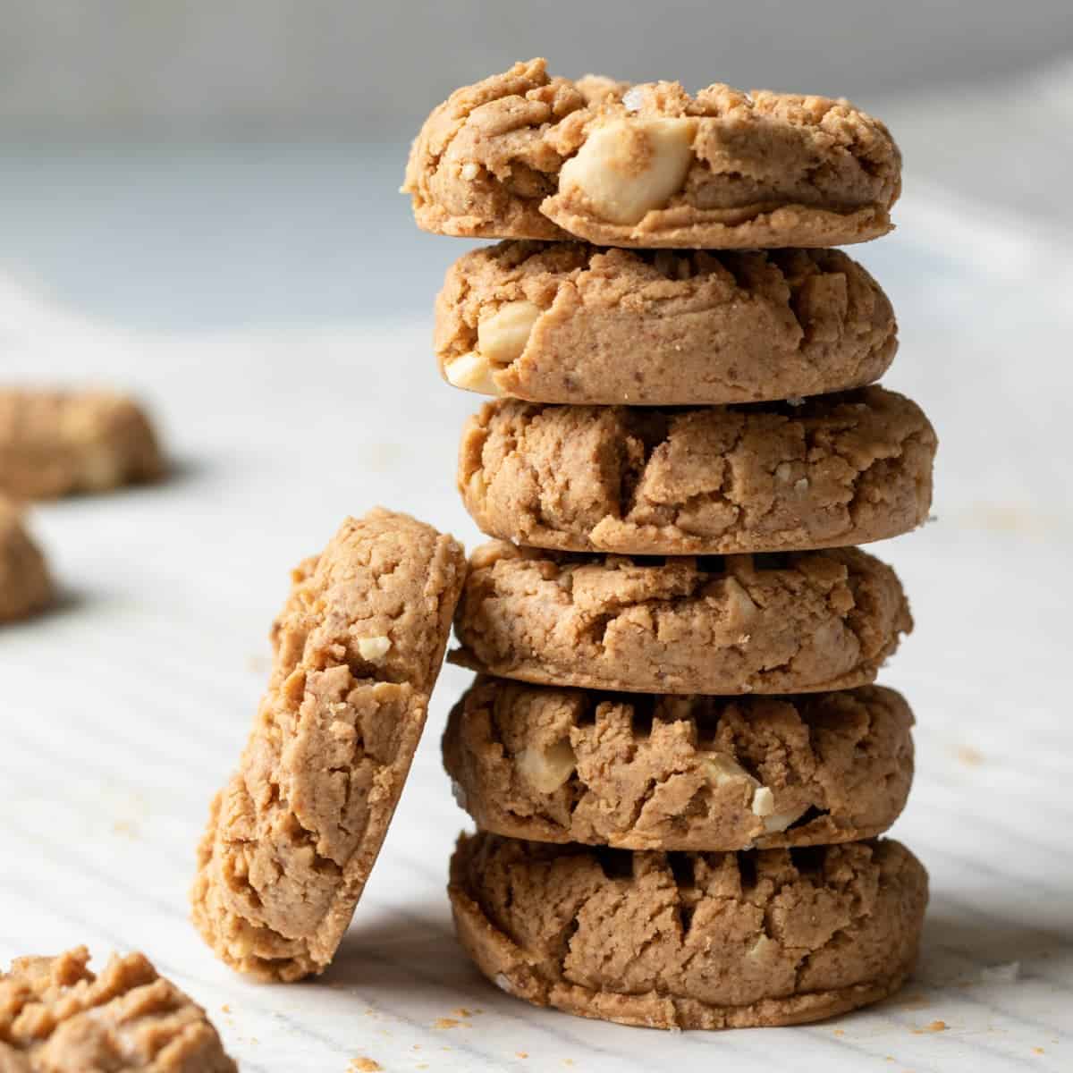 A straight view of six stacked vegan cashew butter cookies with one cookie on the side.