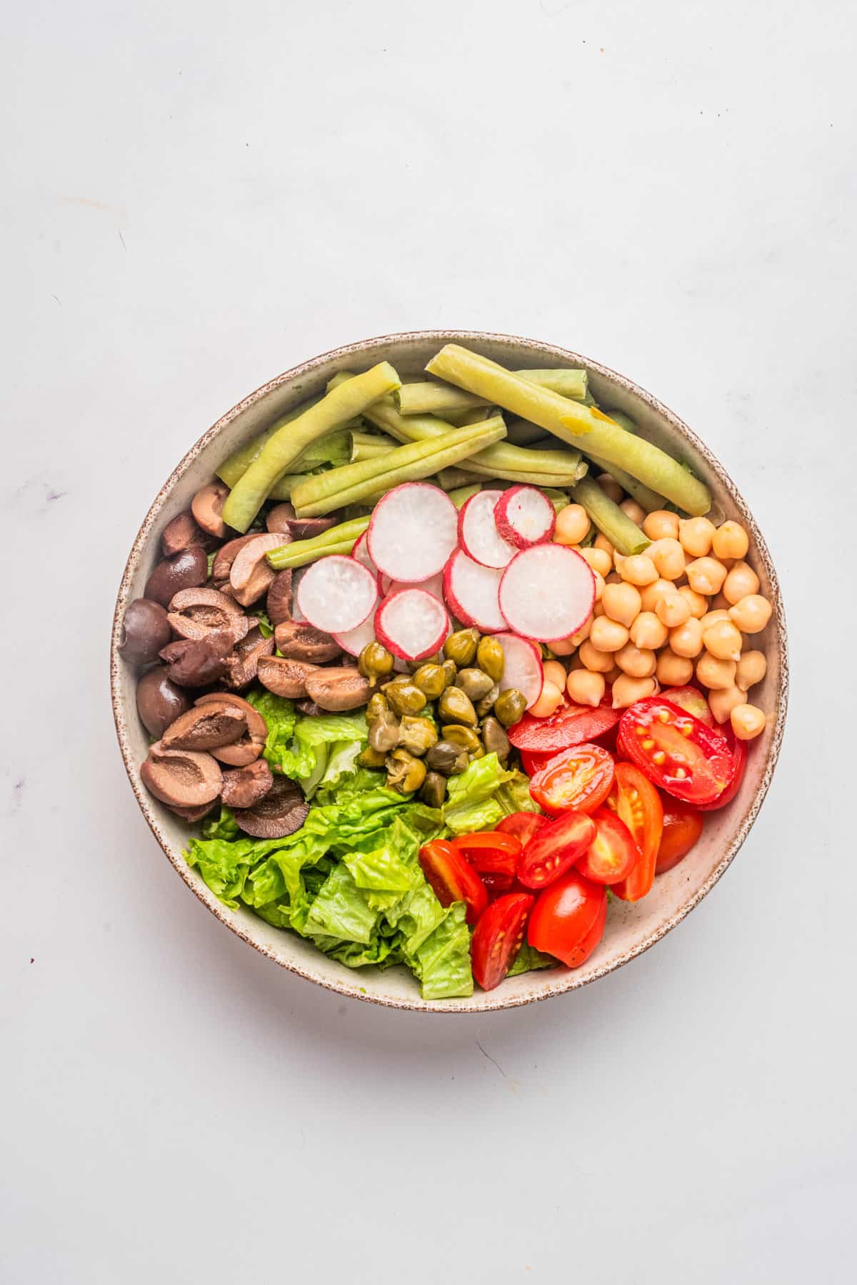 An image of vegan nicoise salad arranged beautifully in a bowl.