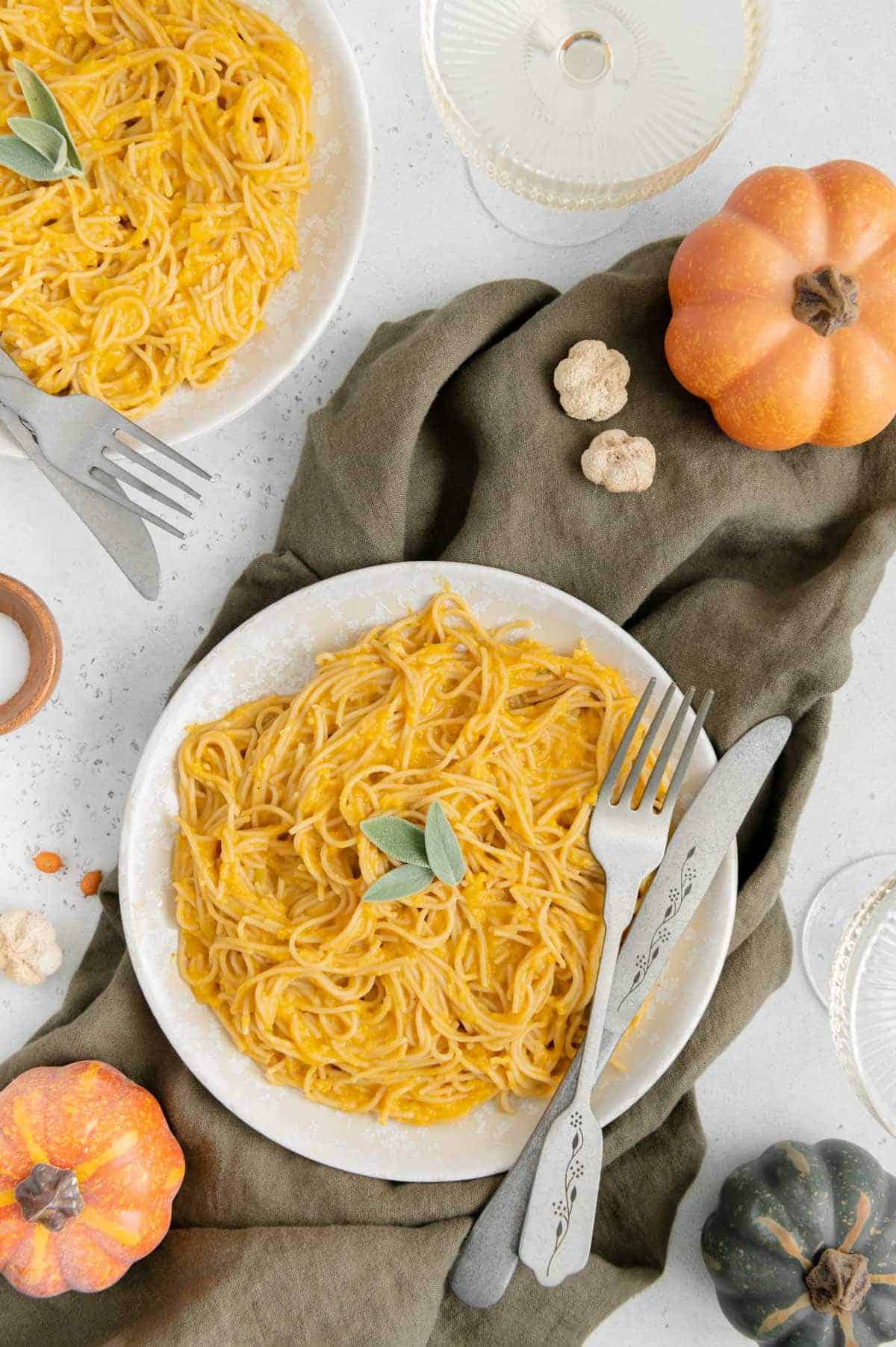 Overhead view of creamy vegan pumpkin pasta with knife and fork.