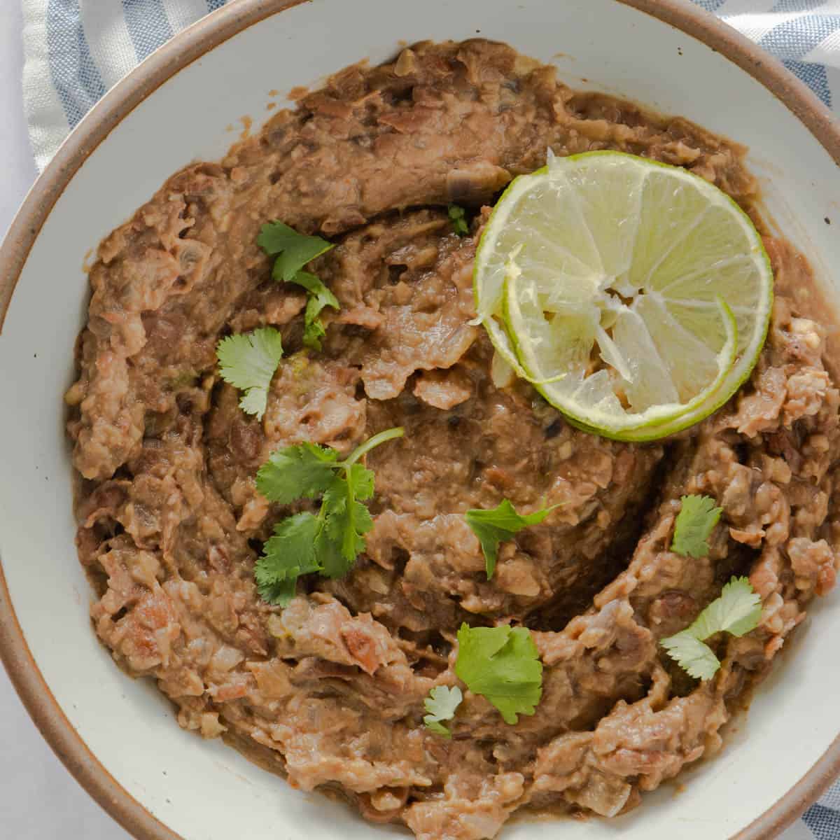 Close up of bowl of refried beans with lime garnish